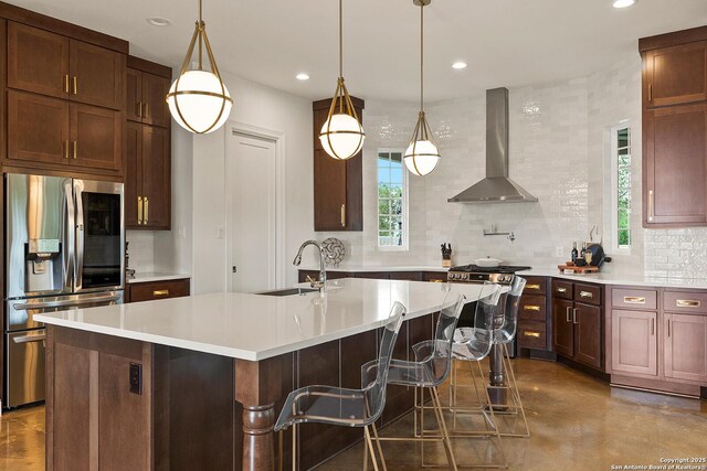 kitchen featuring stainless steel appliances, wall chimney exhaust hood, tasteful backsplash, a sink, and plenty of natural light