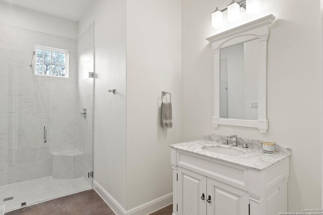 bathroom with a shower stall, vanity, and baseboards