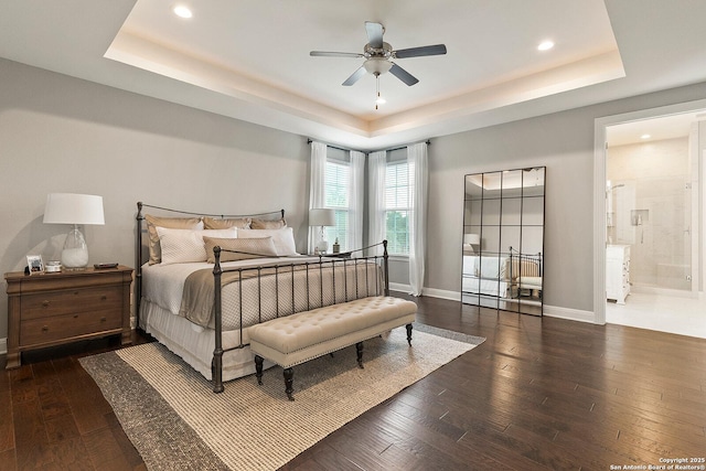 bedroom featuring a raised ceiling, hardwood / wood-style floors, recessed lighting, and baseboards
