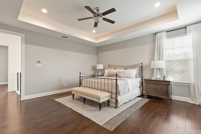 bedroom with a tray ceiling, baseboards, dark wood finished floors, recessed lighting, and a ceiling fan
