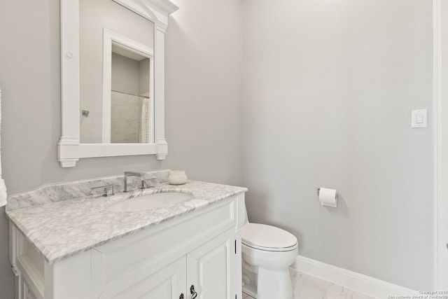 bathroom featuring toilet, vanity, baseboards, and marble finish flooring