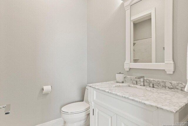 bathroom featuring toilet, vanity, and baseboards