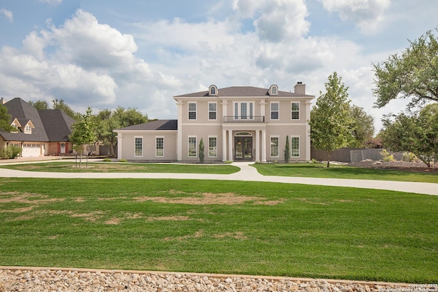 view of front of home with french doors, a chimney, a balcony, and stucco siding