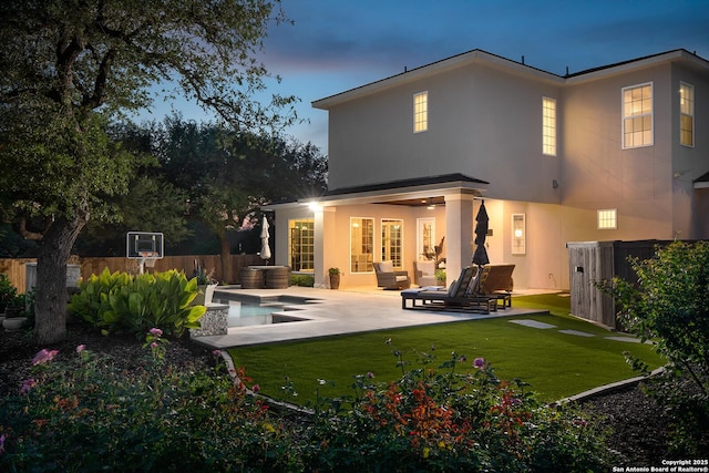 back of house at dusk with a patio and stucco siding
