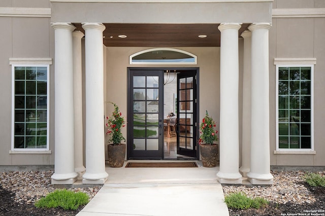 property entrance featuring covered porch, stucco siding, and french doors