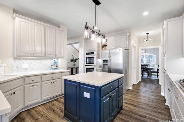 kitchen featuring dark wood-type flooring, appliances with stainless steel finishes, a center island, and white cabinets