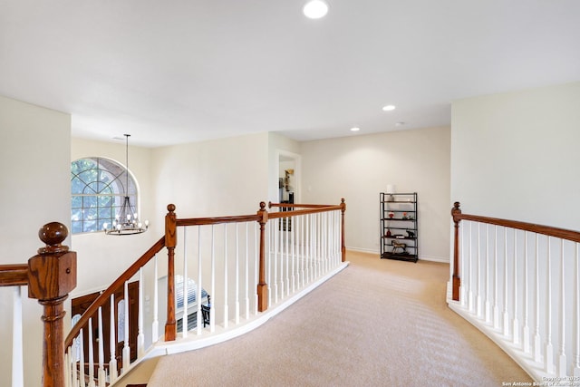 hallway with a notable chandelier and light colored carpet