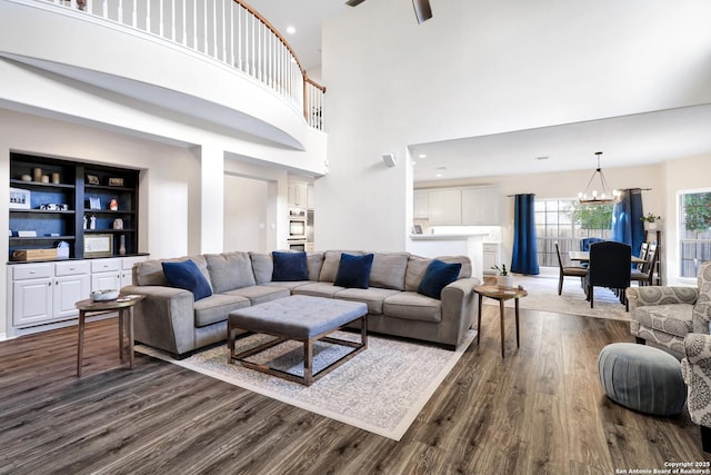 living room with ceiling fan with notable chandelier and dark hardwood / wood-style flooring