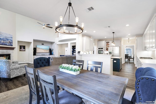 dining room featuring dark wood-type flooring, a fireplace, and ceiling fan