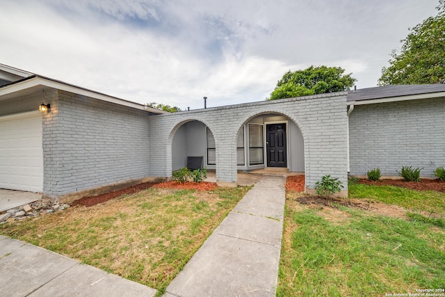 entrance to property with a garage and a lawn