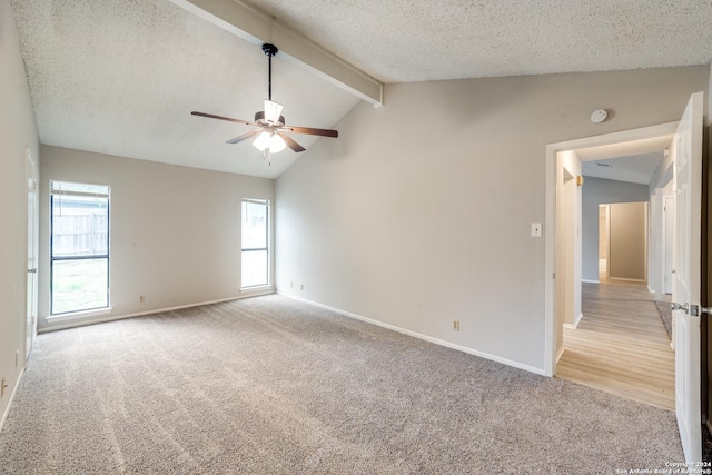 carpeted empty room featuring lofted ceiling with beams, ceiling fan, and a textured ceiling