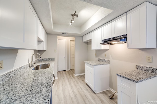 kitchen with sink, light hardwood / wood-style floors, a textured ceiling, white cabinets, and a raised ceiling