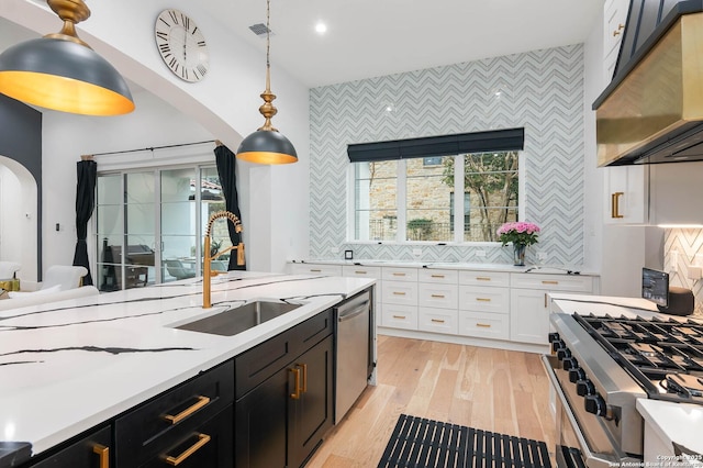 kitchen with sink, appliances with stainless steel finishes, white cabinets, pendant lighting, and backsplash