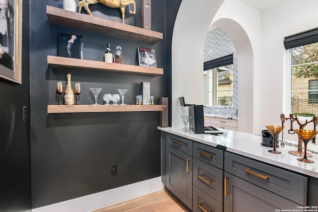 bar featuring gray cabinets, light wood-type flooring, and a wealth of natural light