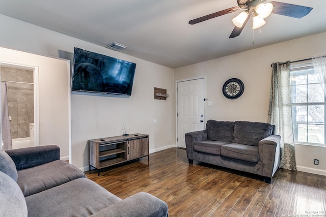 living room with dark hardwood / wood-style flooring, ceiling fan, and a healthy amount of sunlight