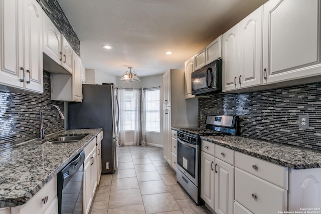 kitchen featuring sink, dark stone countertops, white cabinets, and black appliances