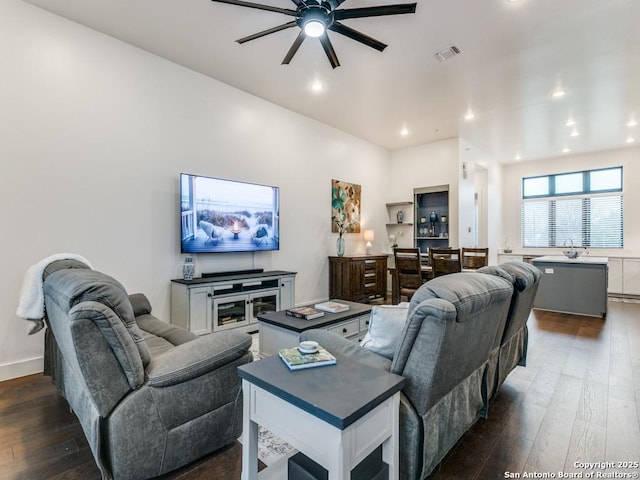 living room featuring dark wood-type flooring and ceiling fan