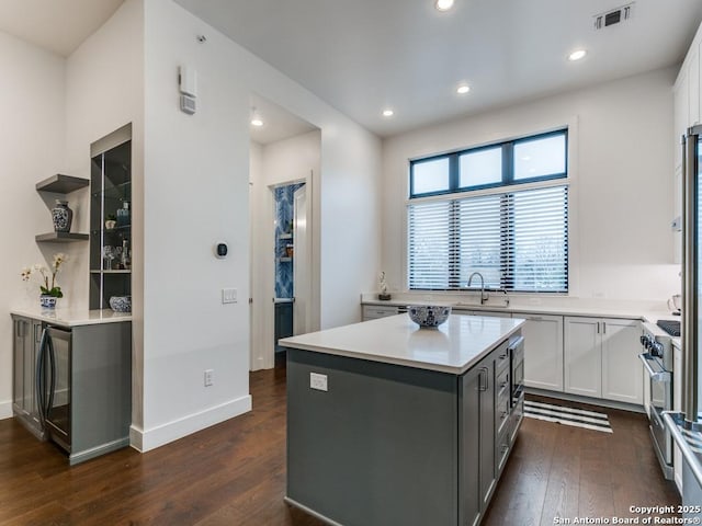 kitchen with white cabinetry, a center island, dark hardwood / wood-style floors, gray cabinets, and high end stove