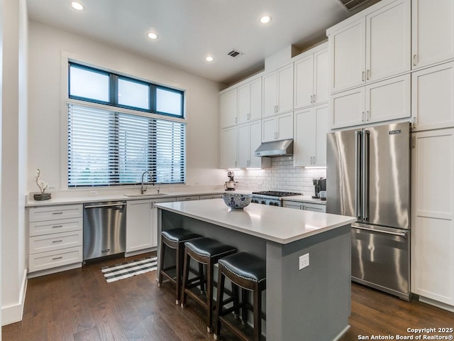 kitchen with a breakfast bar, sink, white cabinetry, appliances with stainless steel finishes, and a kitchen island