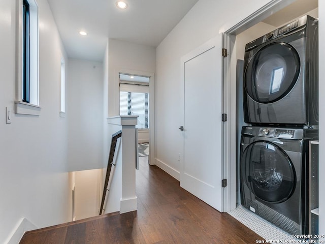 laundry room featuring dark hardwood / wood-style floors and stacked washing maching and dryer