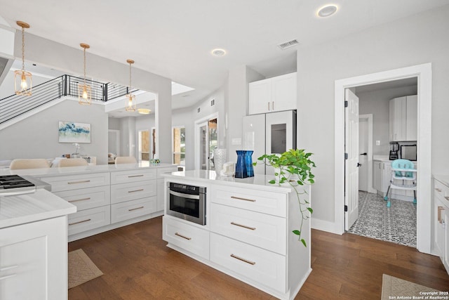 kitchen with dark hardwood / wood-style floors, stainless steel oven, white cabinets, and decorative light fixtures