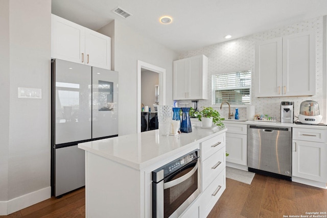 kitchen featuring white cabinetry, dark hardwood / wood-style floors, a center island, and appliances with stainless steel finishes