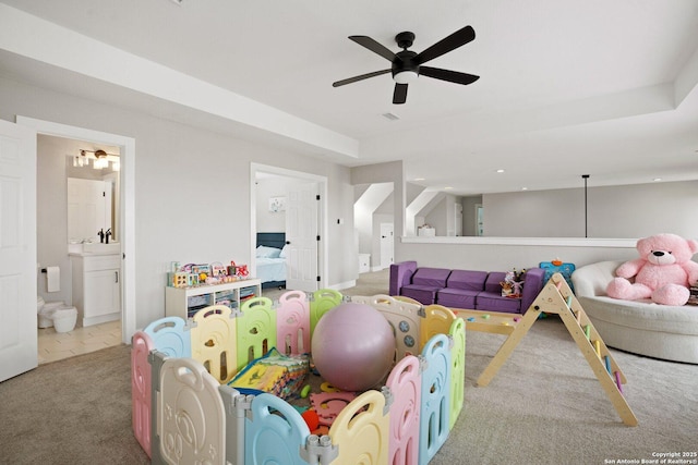 playroom featuring light colored carpet, ceiling fan, and a tray ceiling