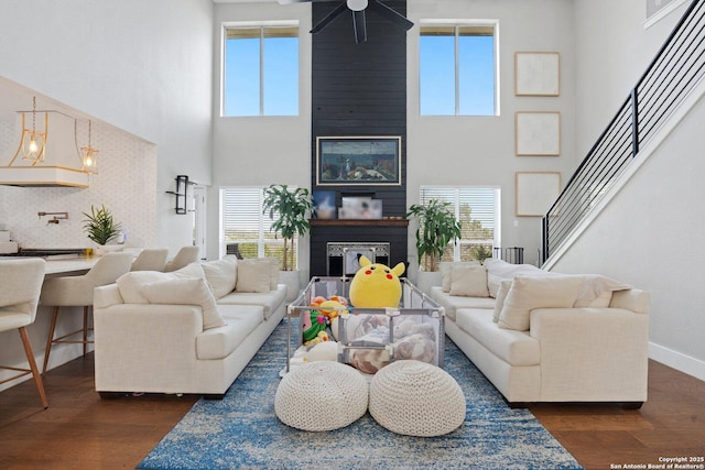 living room featuring ceiling fan, a towering ceiling, a wealth of natural light, and dark hardwood / wood-style flooring