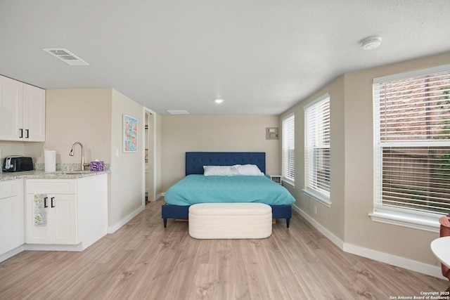 bedroom with sink, light hardwood / wood-style floors, and a textured ceiling