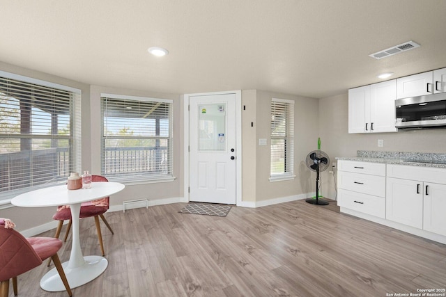 kitchen featuring white cabinetry, light stone counters, and light wood-type flooring