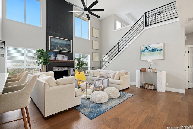 living room featuring a high ceiling, dark wood-type flooring, ceiling fan, and plenty of natural light