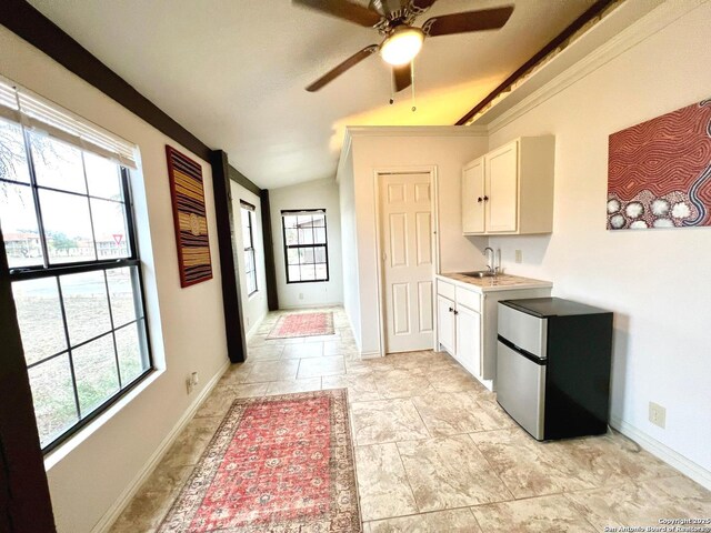 kitchen with stainless steel refrigerator, plenty of natural light, and white cabinets