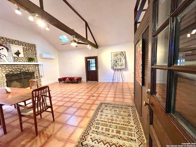 interior space with ceiling fan, beam ceiling, a skylight, a wall unit AC, and a stone fireplace