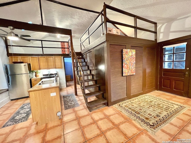 interior space featuring lofted ceiling with beams, ceiling fan, sink, and a textured ceiling