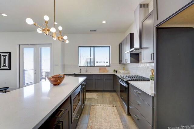 kitchen with pendant lighting, sink, appliances with stainless steel finishes, backsplash, and light wood-type flooring