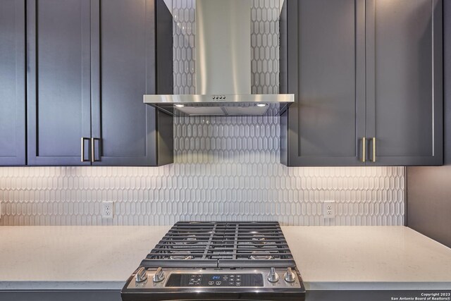 kitchen featuring wall chimney range hood, stainless steel range, and backsplash