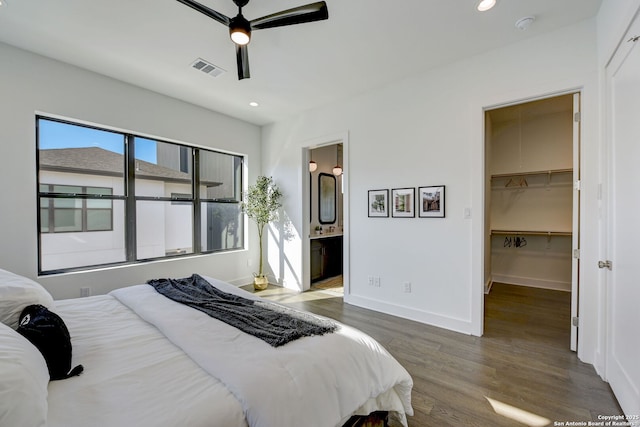 bedroom with ensuite bathroom, dark hardwood / wood-style floors, a spacious closet, ceiling fan, and a closet