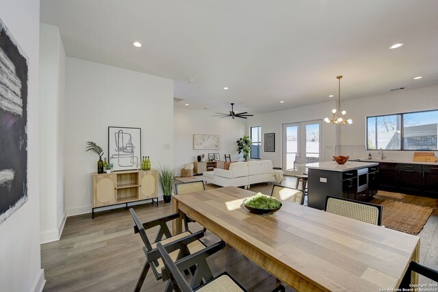 dining space featuring ceiling fan with notable chandelier, french doors, and light wood-type flooring