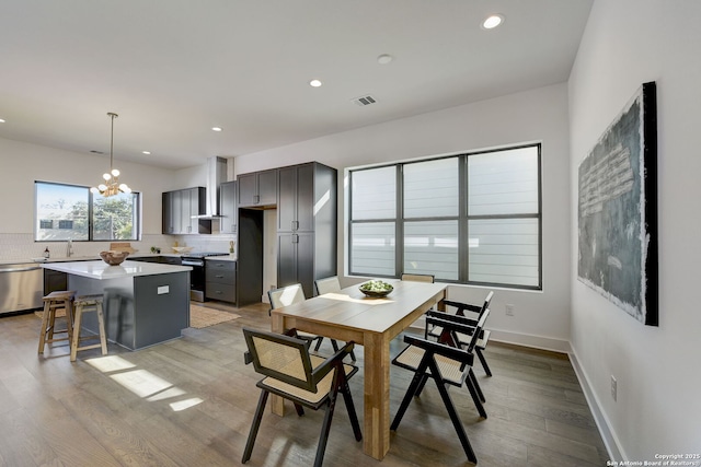 dining area with sink, a notable chandelier, and light hardwood / wood-style flooring