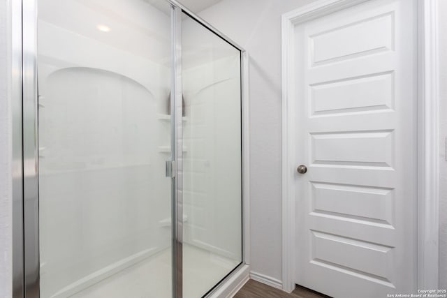 bathroom featuring wood-type flooring and a shower with shower door