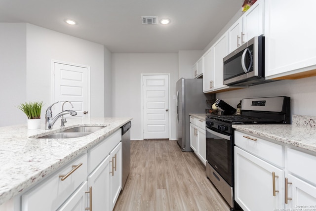 kitchen featuring sink, white cabinetry, light stone counters, light hardwood / wood-style flooring, and stainless steel appliances