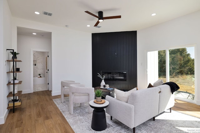 living room with ceiling fan, light wood-type flooring, and a fireplace