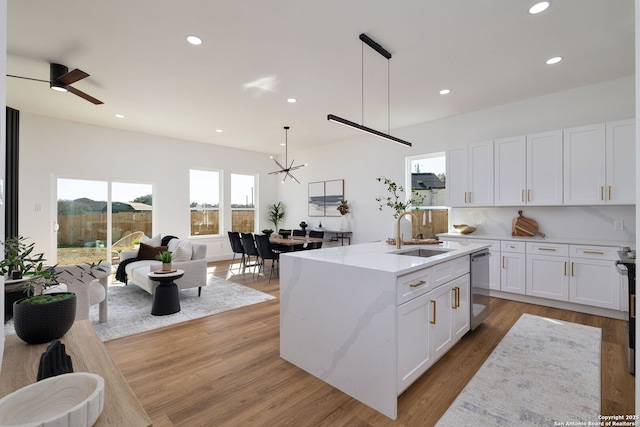 kitchen with pendant lighting, white cabinetry, sink, a kitchen island with sink, and stainless steel dishwasher