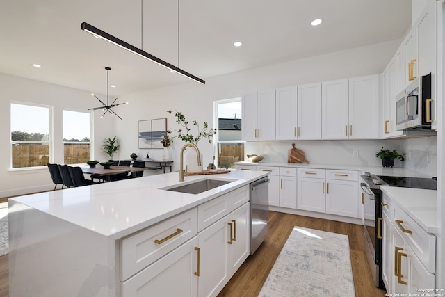 kitchen with stainless steel appliances, sink, an island with sink, and white cabinets