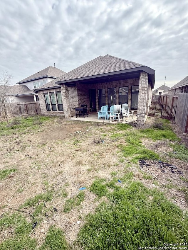 back of property with a patio area, a fenced backyard, a shingled roof, and brick siding