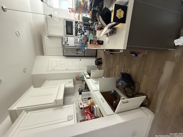 kitchen with light countertops, wainscoting, wooden walls, and white cabinets