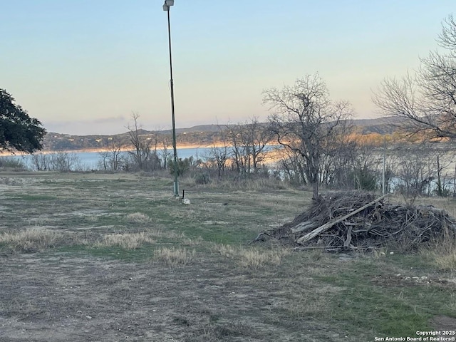 yard at dusk featuring a water view