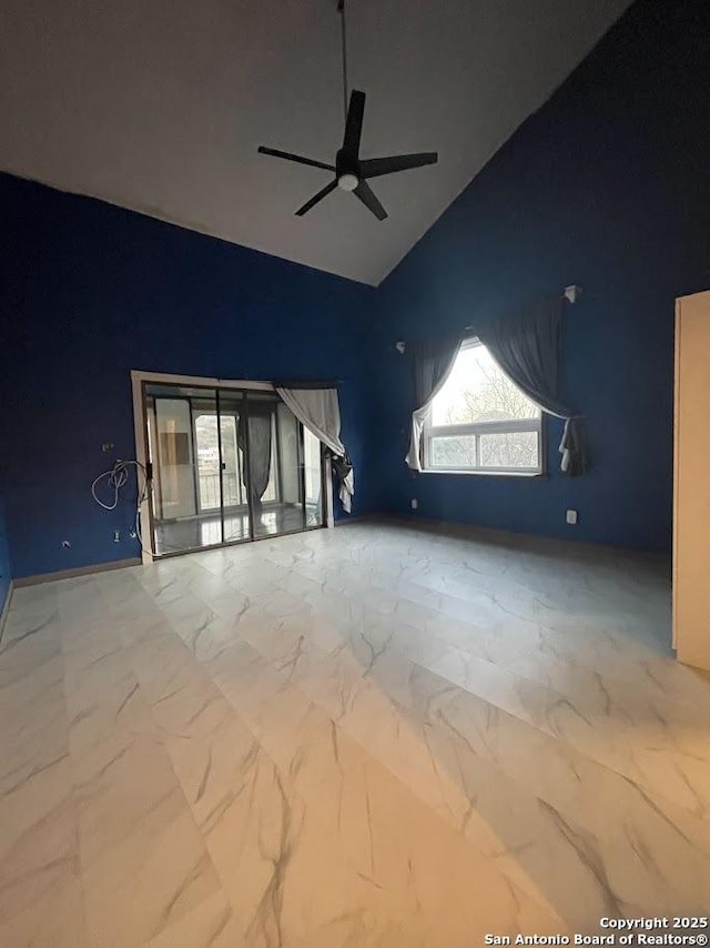 unfurnished living room with ceiling fan and high vaulted ceiling