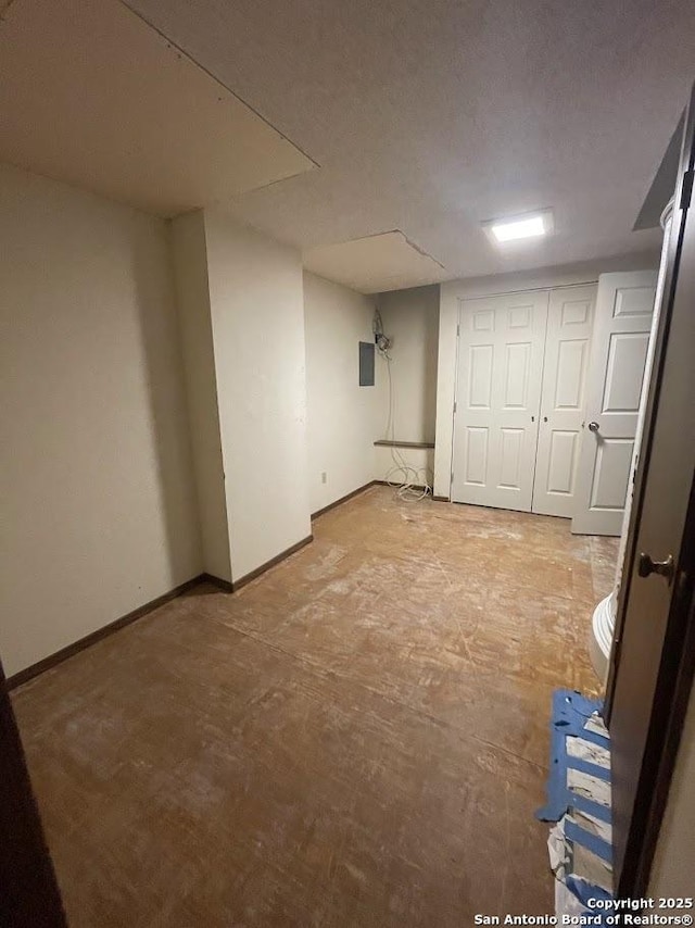 basement featuring electric panel and a textured ceiling