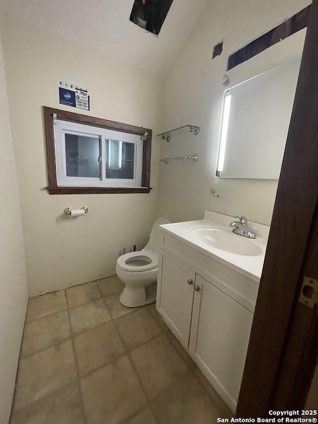 bathroom with lofted ceiling, vanity, and toilet